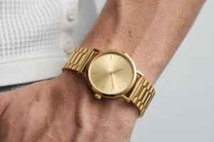 Gold minimalist old money watch dial close-up on wrist with white Henley t-shirt - AURA FASHION